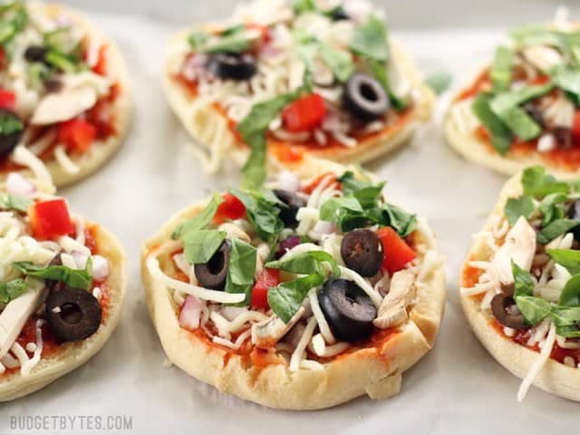 Make Ahead Frozen Mini Pizzas are an easy and inexpensive snack to keep stocked in your freezer. A healthier option to store-bought frozen pizza. BudgetBytes.com Six Freezer Mini Pizzas on a parchment lined baking sheet, ready to be frozen or baked