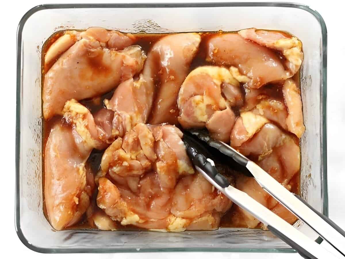 Chicken marinading in a soy marinade in a glass baking dish.