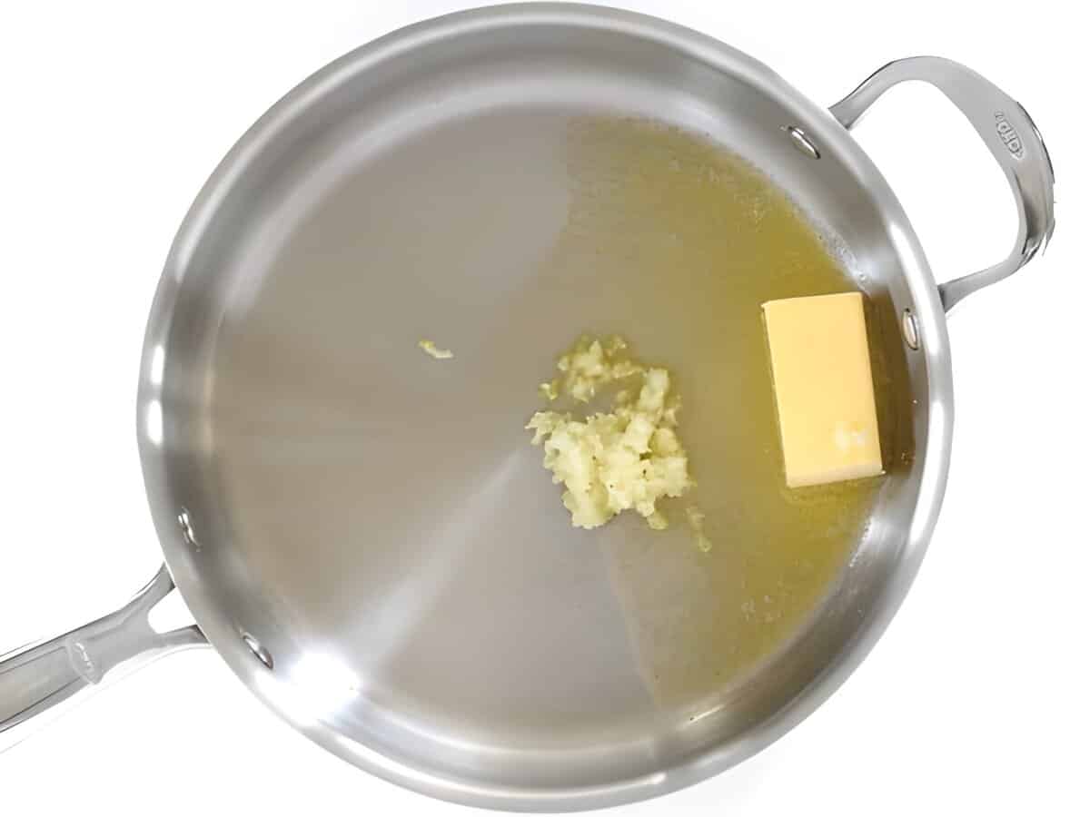 Butter melting in a skillet with minced garlic.