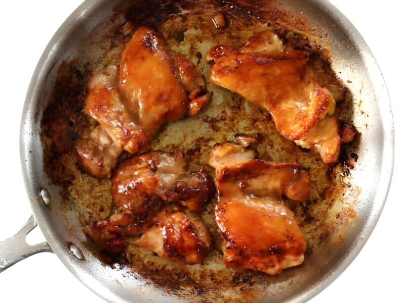 Sticky ginger soy glazed chicken cooking in a skillet.