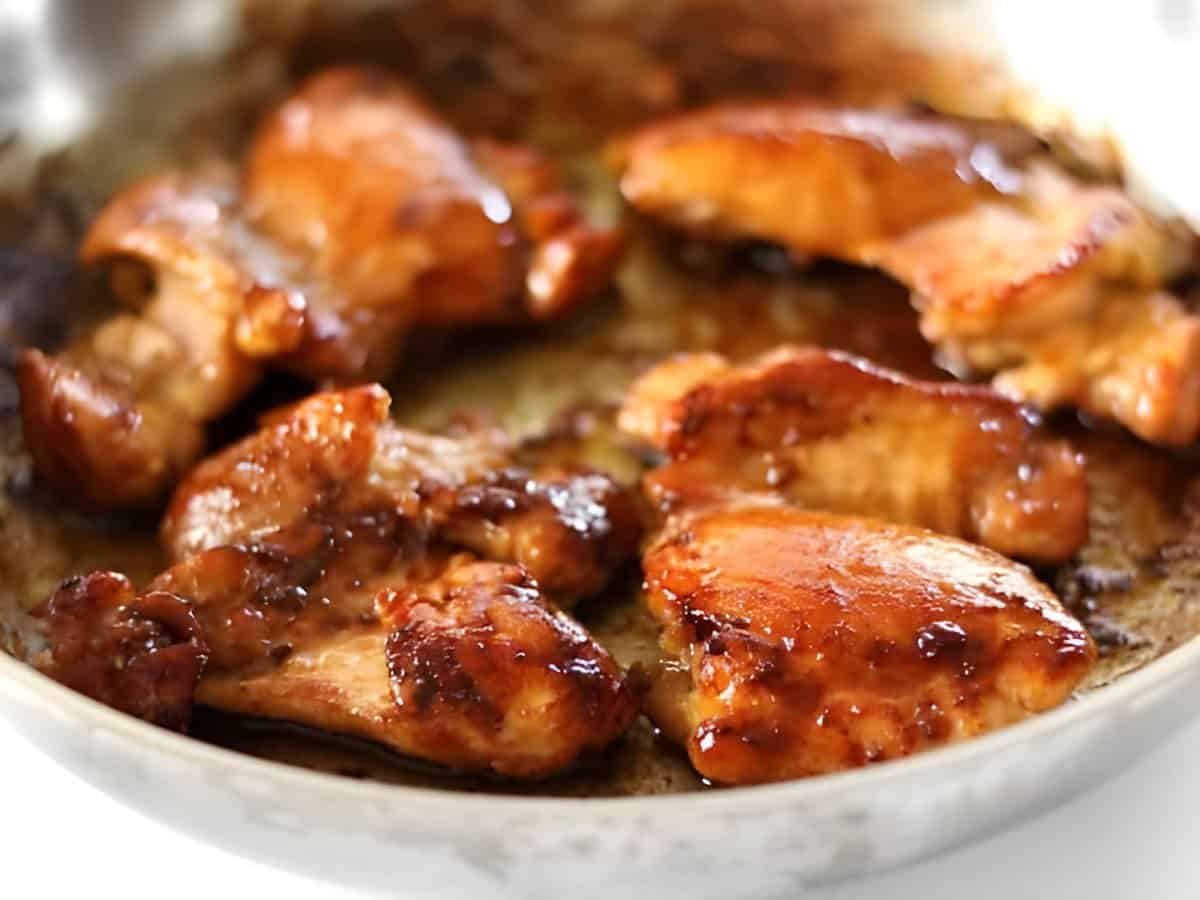 Side view of browned sticky chicken in a skillet.