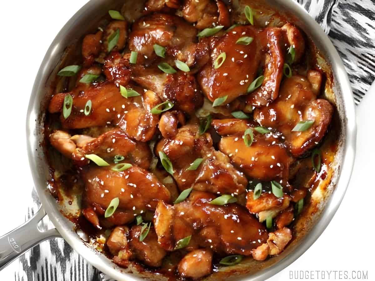 Sticky Ginger Soy Glazed Chicken features and simple marinade that turns into a sticky and delicious glaze. BudgetBytes.com Sticky ginger soy glazed chicken in a skillet with sliced green onions.