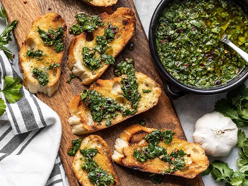 Chimichurri sauce is a tangy, fresh, and garlicky sauce that delivers big flavor to any meal. Use as a marinade, dipping sauce, or condiment. Budgetbytes.com Sliced toasted French bread on a cutting board drizzled with chimichurri with a bowl of chimichurri sauce on the side.