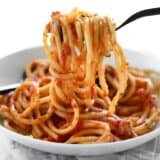 Side view of a plate of spaghetti and butter tomato sauce.