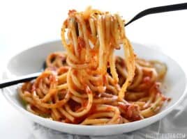 Side view of a plate of spaghetti and butter tomato sauce.