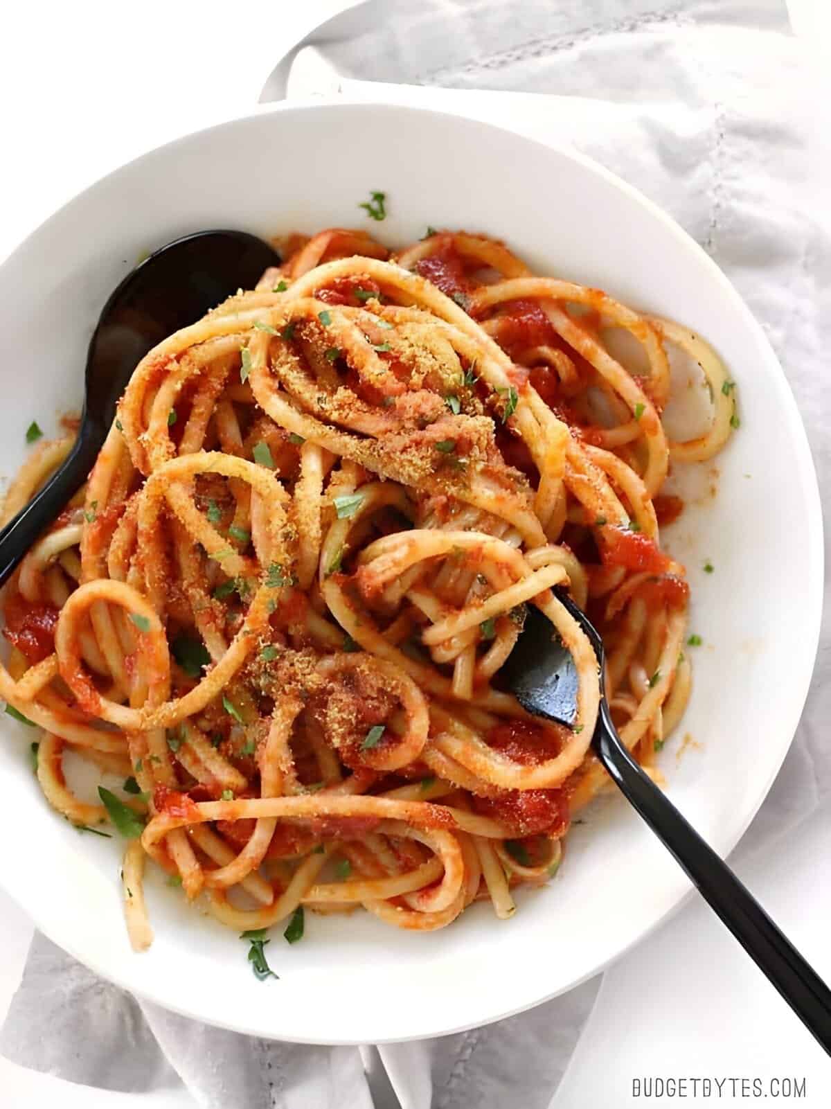 Overhead view of pasta with butter tomato sauce on a plate with a fork.