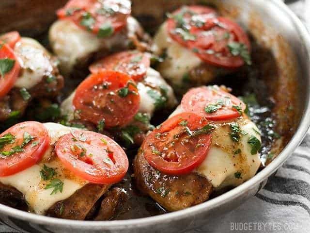 A simple marinade, creamy mozzarella, and fresh tomatoes turn simple chicken thighs into a fast and easy weeknight dinner in this Balsamic Chicken Skillet. BudgetBytes.com Side view of balsamic chicken in the skillet with melty mozzarella and tomato slices on top