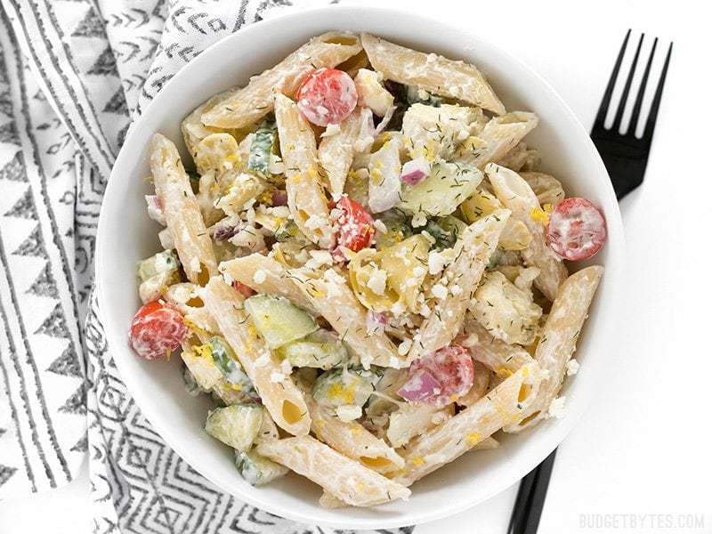 Creamy Lemon Dill Greek Pasta Salad is packed with bold flavors and fresh vegetables, making it a delicious light lunch or cold summer meal. BudgetBytes.com Overhead view of Creamy Lemon Dill Greek Pasta Salad with a black fork on the side