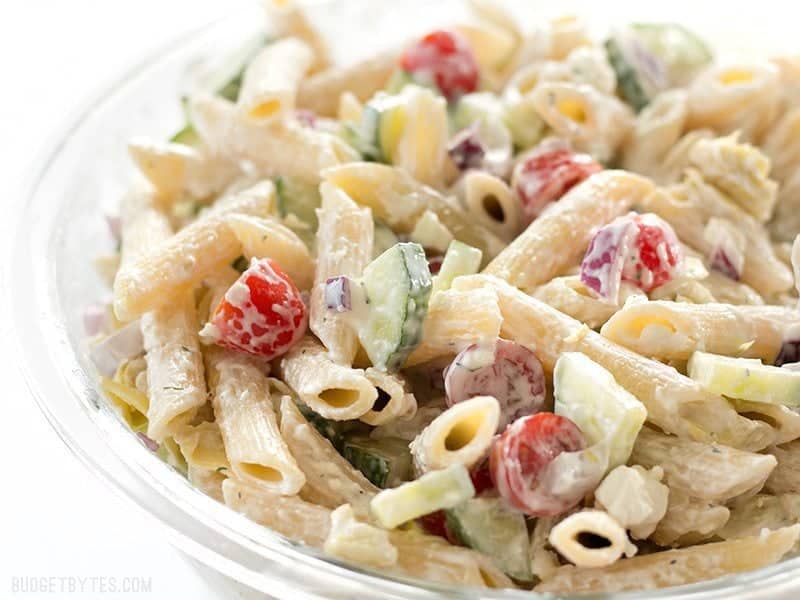 Creamy Lemon Dill Greek Pasta Salad is packed with bold flavors and fresh vegetables, making it a delicious light lunch or cold summer meal. BudgetBytes.com Side view of Creamy Lemon Dill Greek Pasta Salad in a glass bowl