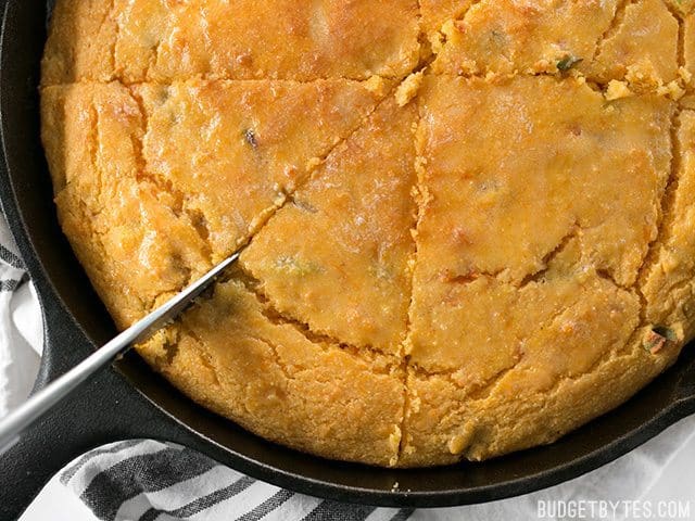 Close up of slicing Hatch Chile Sweet Potato Cornbread in skillet