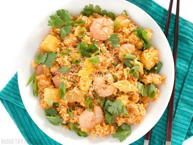 Shrimp Fried Rice with Pineapple and Toasted Coconut is a fast and easy alternative to takeout, perfect for busy weeknights! BudgetBytes.com Overhead view of a bowl of Shrimp Fried Rice with Pineapple and Toasted Coconut on a teal napkin