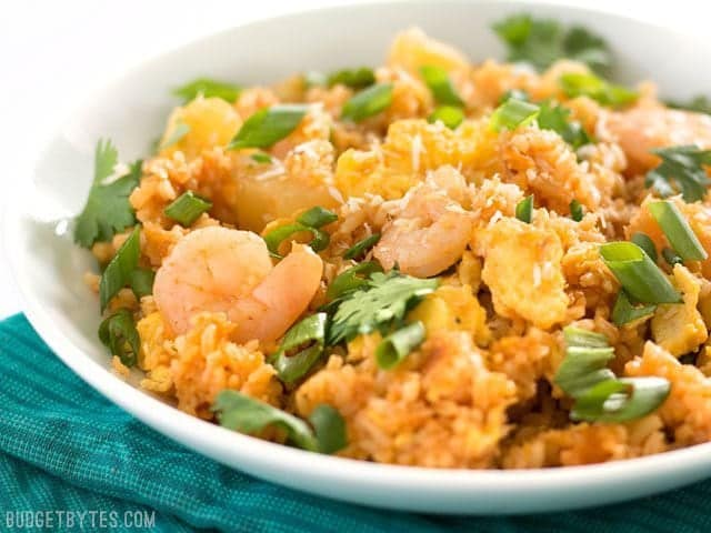 Shrimp Fried Rice with Pineapple and Toasted Coconut is a fast and easy alternative to takeout, perfect for busy weeknights! BudgetBytes.com Close up side view of a bowl of Shrimp Fried Rice with Pineapple and Toasted Coconut