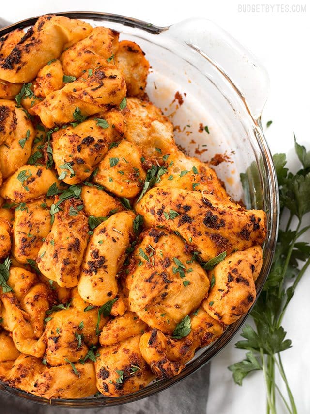 Tomato Herb Pull Apart Bread combines a rich and tangy tomato sauce, savory Parmesan, and fresh bread dough for an irresistible appetizer loaf. BudgetBytes.com Overhead view of the baking dish full of Tomato Herb Pull Apart Bread, with a couple pieces missing
