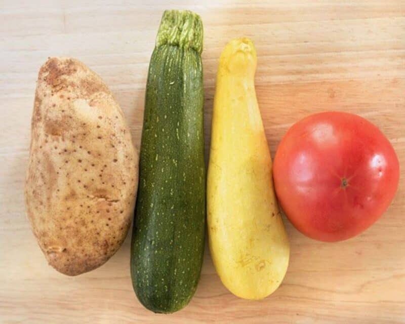 A potato, a zucchini, a summer squash, and a tomato.