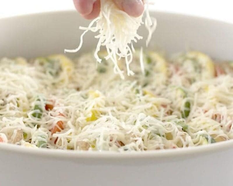 Sprinkling cheese over the vegetables.