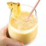 Hand holding a pineapple orange Julius drink.