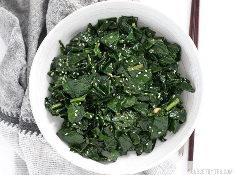 Sesame Kale is a quick, easy, and satisfying side dish that pairs perfectly with any Asian inspired meal. BudgetBytes.com Finished Sesame Kale in a bowl with chopsticks on the side