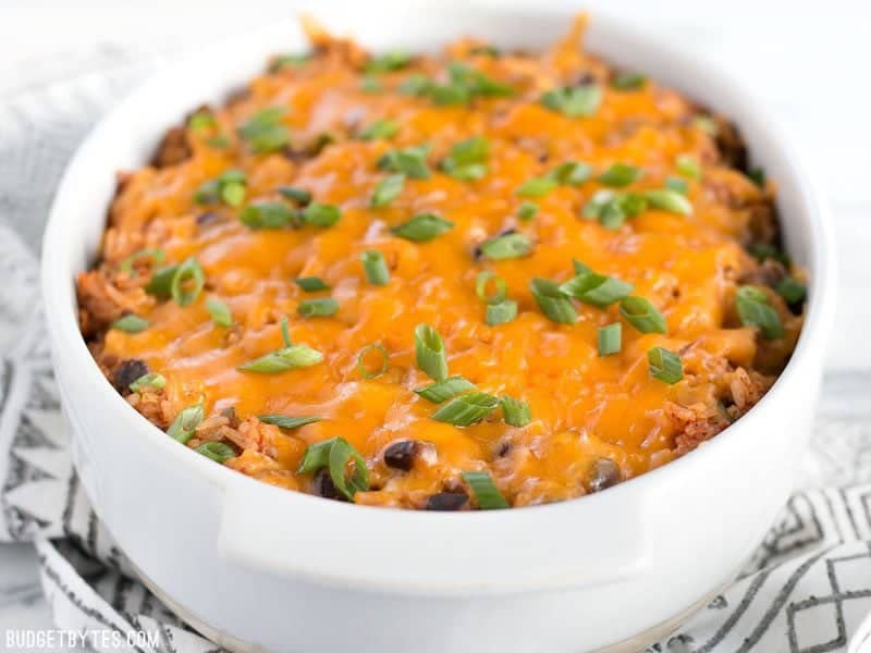This Beef Burrito Casserole is totally customizable and can include all your favorite burrito or nacho toppings. Leftovers reheat great for lunch! Budgetbytes.com Front view of Beef Burrito Casserole in the casserole dish, topped with sliced green onions.