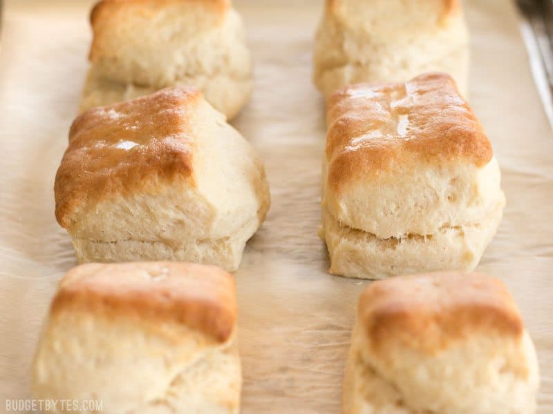 5 Ingredient Freezer Biscuits are the fastest and easiest way to have fresh, warm, and fluffy biscuits for breakfast any day of the week. BudgetBytes.com Side view of freshly baked Freezer Biscuits on a parchment lined baking sheet