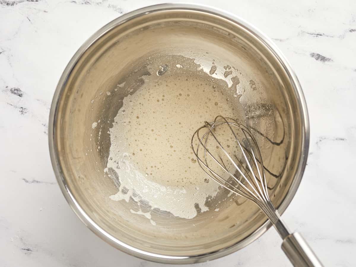 Whisked egg white with vanilla extract in a bowl.