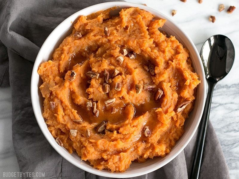 Maple Brown Butter Mashed Sweet Potatoes are a simple way to add a little something extra special to your Thanksgiving table. Easy, delicious, elegant. Budgetbytes.com A bowl full of Maple Brown Butter Mashed Sweet Potatoes with pecans.