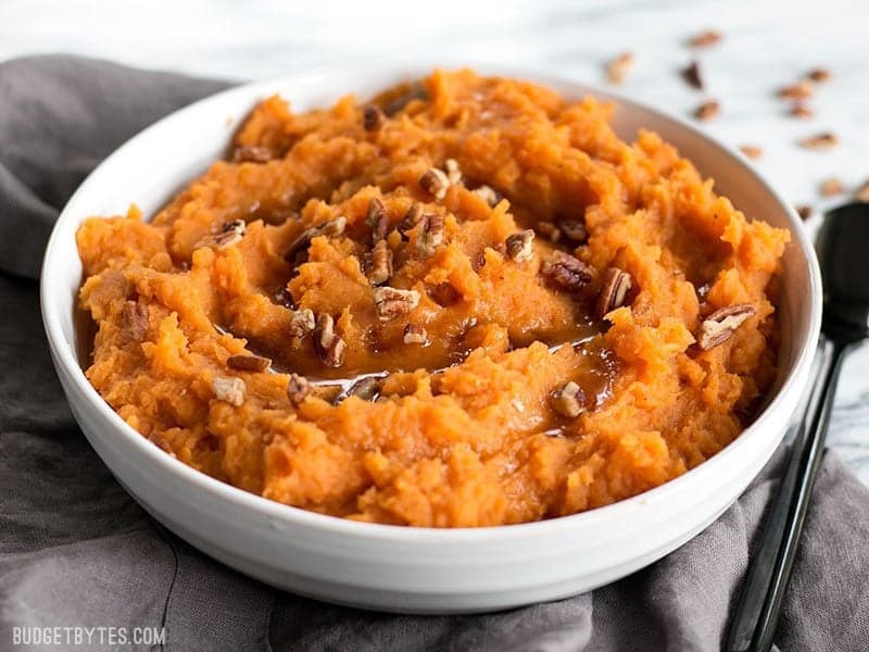 Maple Brown Butter Mashed Sweet Potatoes are a simple way to add a little something extra special to your Thanksgiving table. Easy, delicious, elegant. Budgetbytes.com Front view of Maple Brown Butter Mashed Sweet Potatoes with pecans.