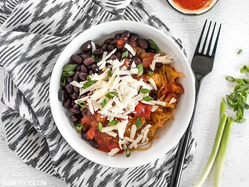 Spaghetti squash makes a great fiber-filled low-carb substitute for rice in these Southwest Spaghetti Squash Bowls. BudgetBytes.com Finished southwest spaghetti squash bowl topped with cheese, a sliced green onion on the side.