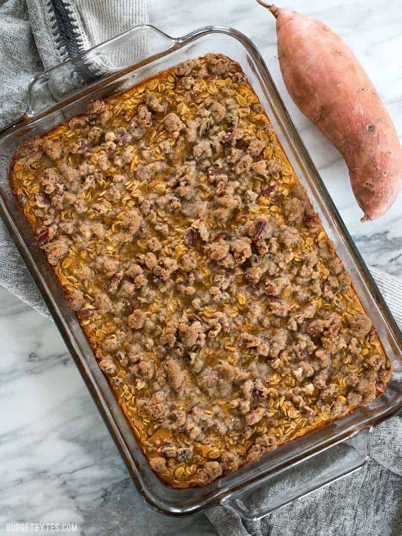 Sweet Potato Casserole Baked Oatmeal is a great way to have your favorite Thanksgiving side as a nutrient packed breakfast. BudgetBytes.com A full casserole dish of Sweet Potato Casserole Baked Oatmeal with a whole sweet potato on the side.