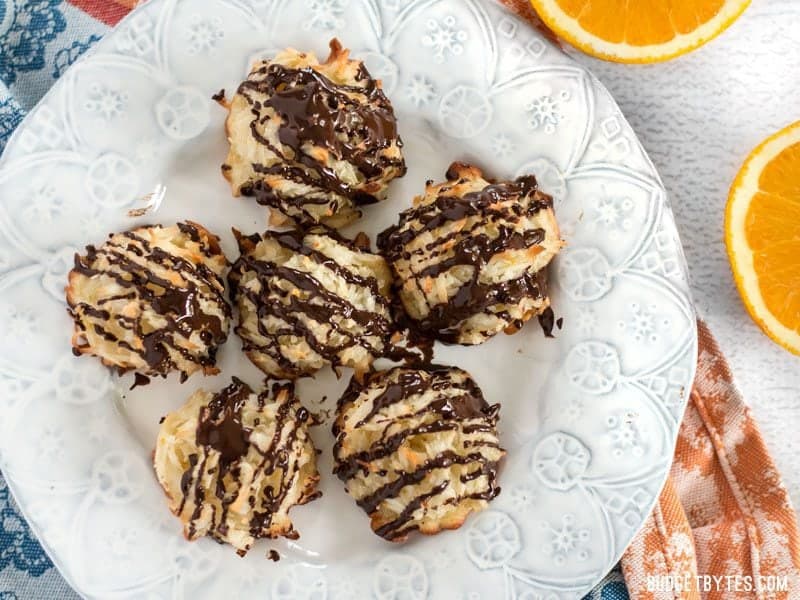 These Chocolate Glazed Macaroons feature a combination of vanilla, almond, and fresh orange zest for an extra fragrant and flavorful cookie. Budgetbytes.com Six Chocolate Glazed Macaroons on a plate, viewed from above, with fresh oranges on the side