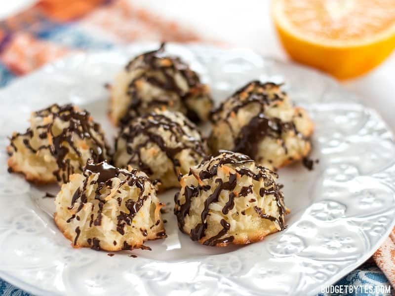 These Chocolate Glazed Macaroons feature a combination of vanilla, almond, and fresh orange zest for an extra fragrant and flavorful cookie. Budgetbytes.com A plate full of Chocolate Glazed Macaroons with a fresh orange in the background