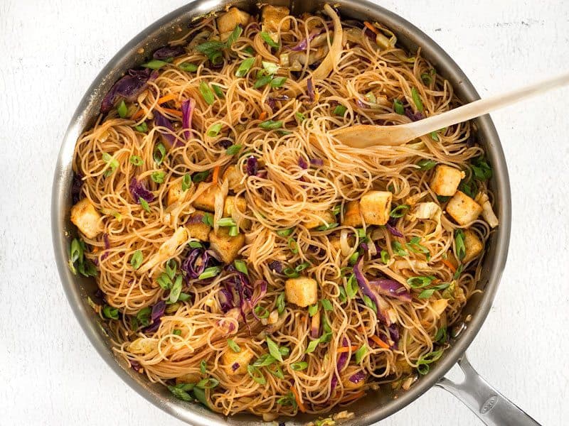 These Singapore Noodles with Crispy Tofu have a bold flavor and vibrant colors thanks to shredded vegetables and a bright curry sauce. BudgetBytes.com Finished Singapore Noodles with Crispy Tofu in the skillet with a wooden pasta fork