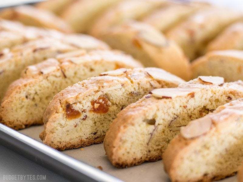 Fresh homemade Almond Apricot Biscotti are pennies a piece and can be stored in the freezer, ready for dunking at any time. BudgetBytes.com Freshly baked Almond Apricot Biscotti still on the baking sheet, viewed from the side
