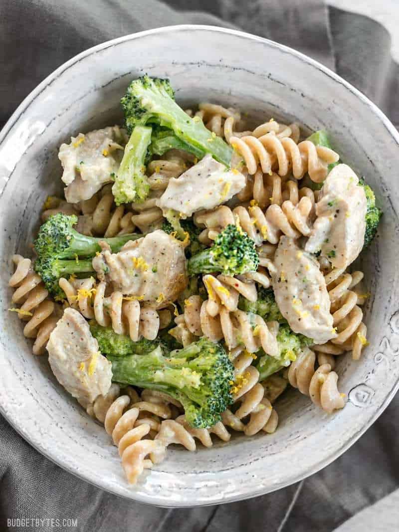 This super luscious Chicken and Broccoli Pasta with Lemon Cream Sauce comes together quickly for a weeknight dinner and uses only a few simple ingredients. BudgetBytes.com Close up overhead shot of Chicken and Broccoli Pasta with Lemon Cream Sauce garnished with lemon zest