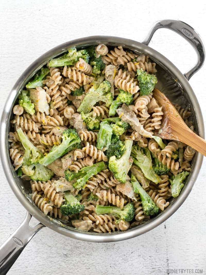 This super luscious Chicken and Broccoli Pasta with Lemon Cream Sauce comes together quickly for a weeknight dinner and uses only a few simple ingredients. BudgetBytes.com Finished Chicken and Broccoli Pasta with Lemon Cream Sauce in the skillet with a wooden spoon