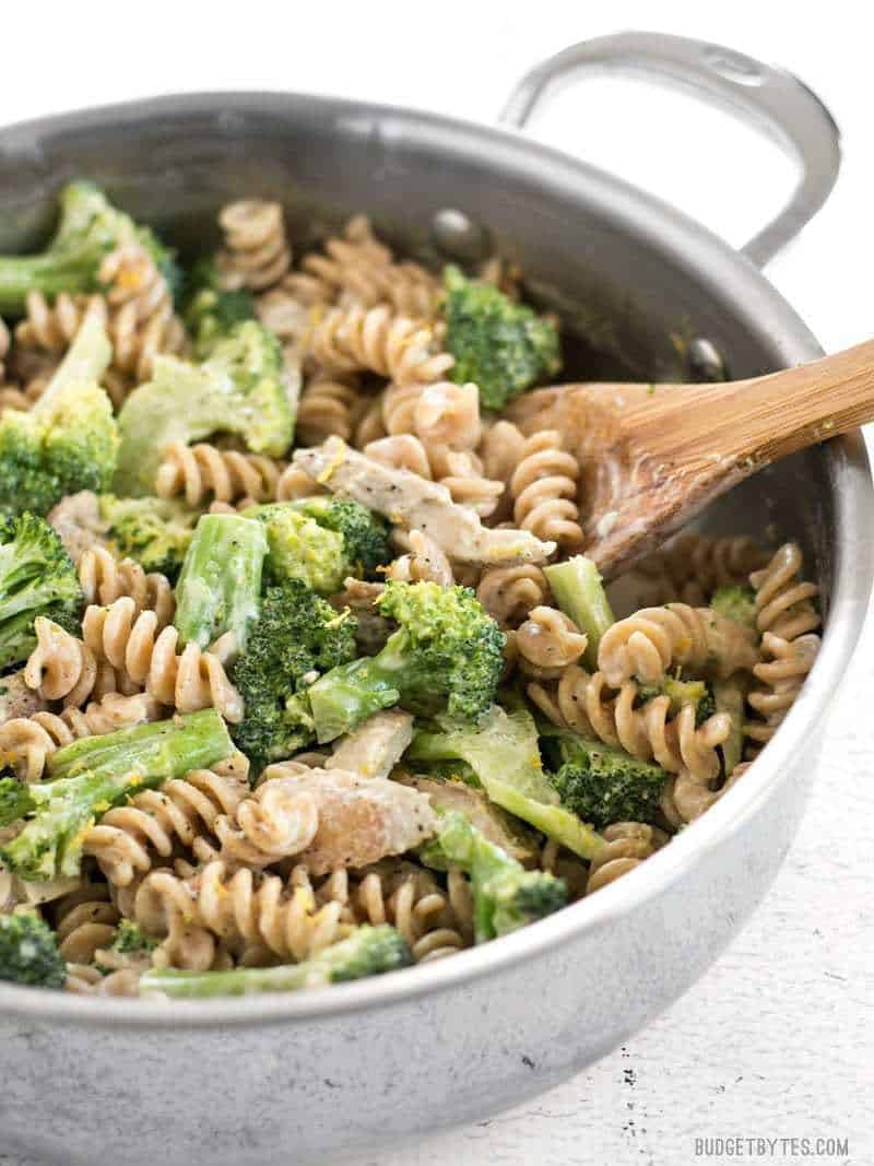 This super luscious Chicken and Broccoli Pasta with Lemon Cream Sauce comes together quickly for a weeknight dinner and uses only a few simple ingredients. BudgetBytes.com Side view of Chicken and Broccoli Pasta with Lemon Cream Sauce in the skillet with a wooden spoon