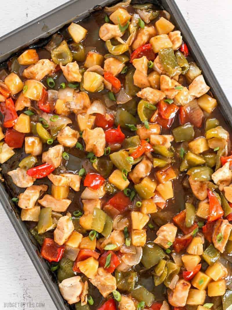 This oven baked Sheet Pan Sweet and Sour Chicken is a little more forgiving than a fast moving, high heat stir fry, making it great for beginners! BudgetBytes.com Sheet Pan Sweet and Sour Chicken still on the sheet pan, drenched in sauce