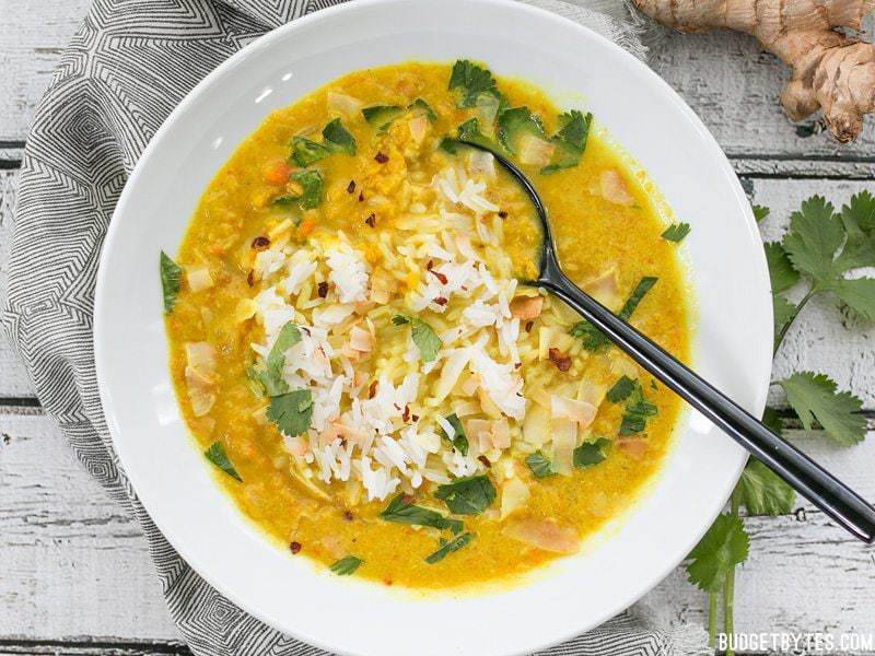 Golden Coconut Lentil Soup is a light and fresh vegan soup with vibrant turmeric and a handful of fun toppings. Step by step photos. Budgetbytes.com Overhead shot of a bowl of Golden Coconut Lentil Soup