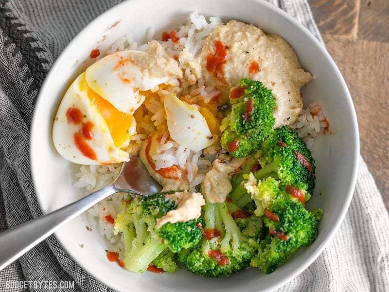 Hummus Breakfast Bowls are a medley of colors, flavors, and textures, and a great way to work vegetables into the most important meal of the day. BudgetBytes.com Overhead view of a Hummus Breakfast Bowl being eaten with a fork