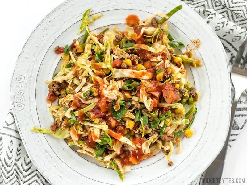 This Southwest Beef and Cabbage Stir Fry is a fast, easy, and flavorful way to make sure dinner is filled with plenty of vegetables. BudgetBytes.com A white plate full of Southwest Beef and Cabbage Stir Fry with taco sauce drizzled over top