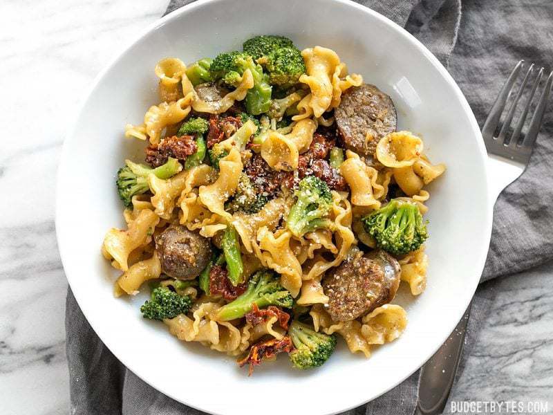 This One Pot Sausage and Sun Dried Tomato Pasta cooks quickly and in one skillet so that no flavor is lost! Make dinner fast, easy, and delicious. BudgetBytes.com A bowl of One Pot Sausage and Sun Dried Tomato Pasta with a fork on the side
