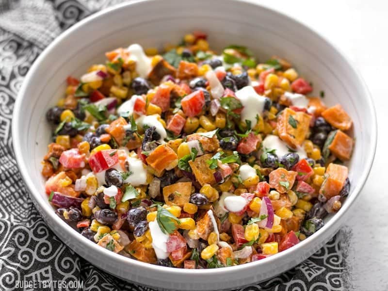 This Roasted Sweet Potato Rainbow Salad combines a medley of vibrant colors and flavors, brought together by a bright and creamy dressing. BudgetBytes.com A bowl of Roasted Sweet Potato Rainbow Salad viewed from the front