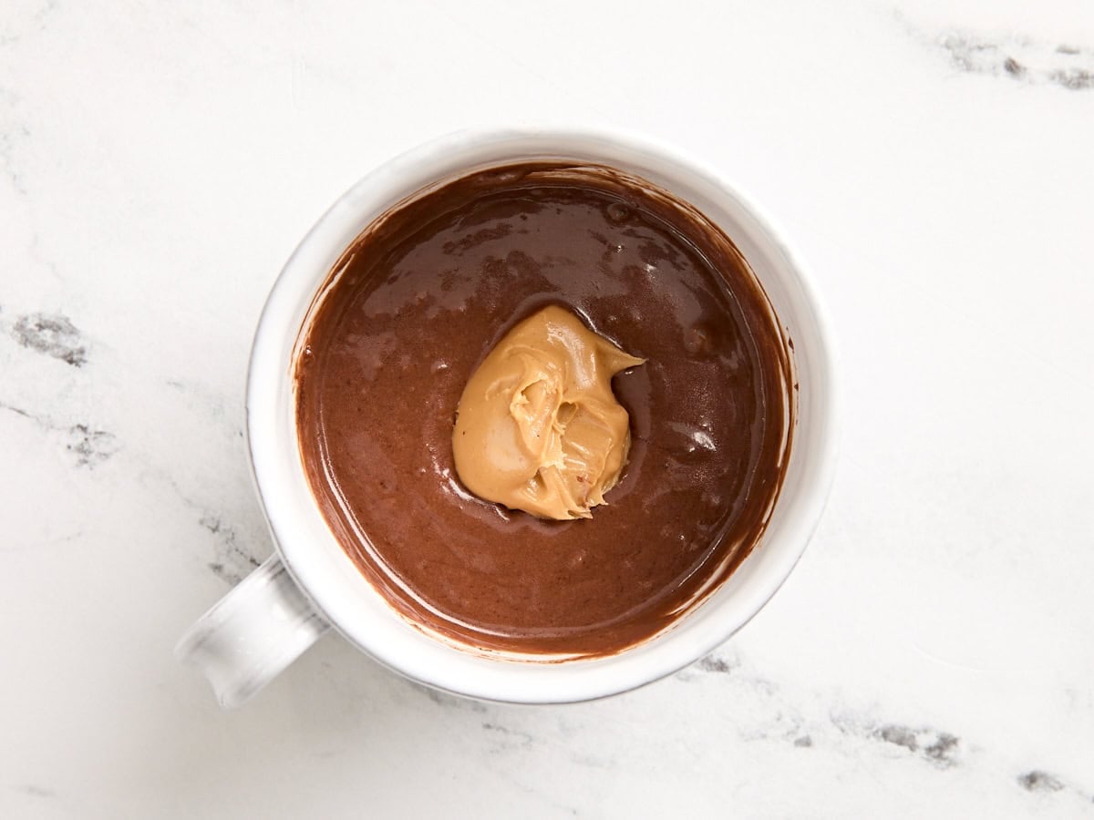 A dollop of peanut butter added to the center of the batter for a the batter for chocolate mug cake.