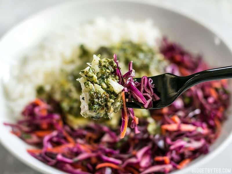 These light and fresh Baked Chimichurri Fish Bowls are simple to prepare and make great cold lunches for the rest of the week. BudgetBytes.com Close up of a forkful of baked chimichurri fish and slaw