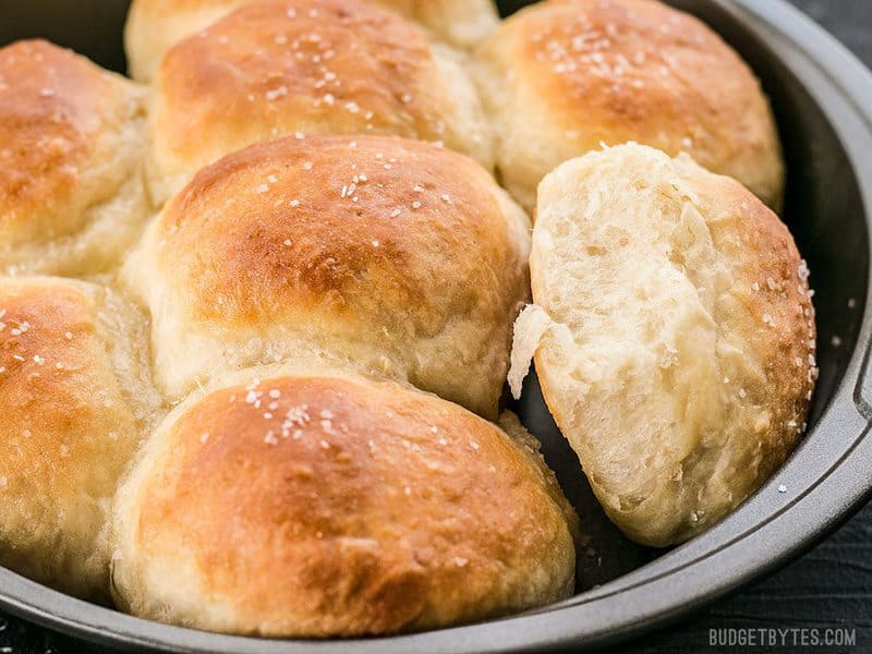 These incredible light and delicate Buttermilk Pull-Apart Rolls couldn't be easier thanks to a simple no-knead dough. BudgetBytes.com Close up side view of Buttermilk Pull-Apart Rolls in the round baking pan