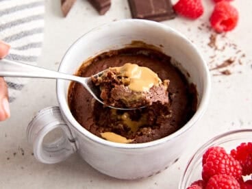 Side view of a chocolate mug cake with a spoon taking some.