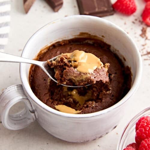 Side view of a chocolate mug cake with a spoon taking some.