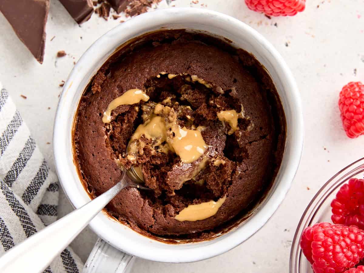 Overhead view of a chocolate and peanut butter mug cake, with a spoon in the center.