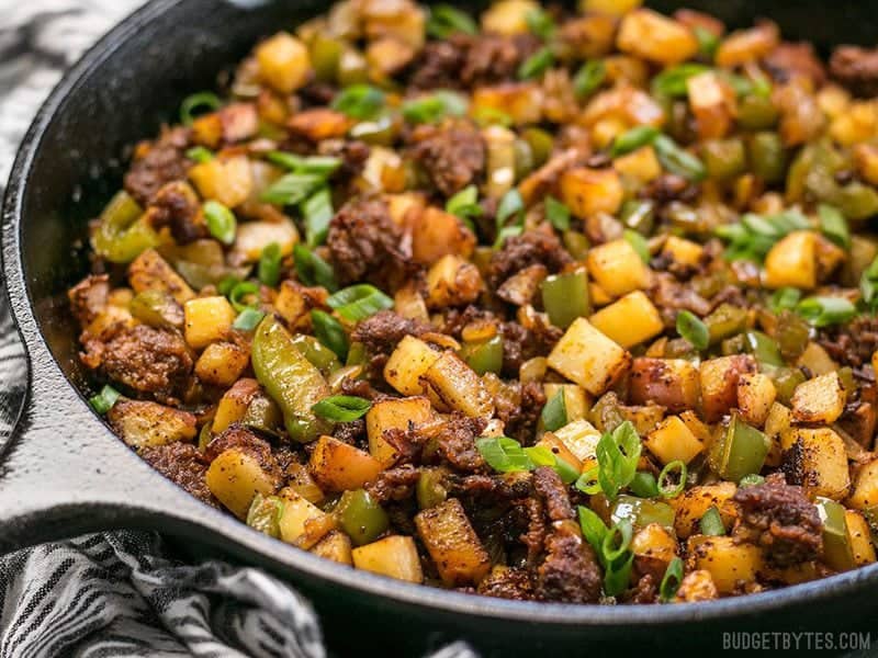 This simple but tasty Chorizo Breakfast Hash is a breakfast classic. Perfect for your lazy weekend brunch, or even "breakfast for dinner". BudgetBytes.com Close up of Chorizo Breakfast Hash in a cast iron skillet from the side