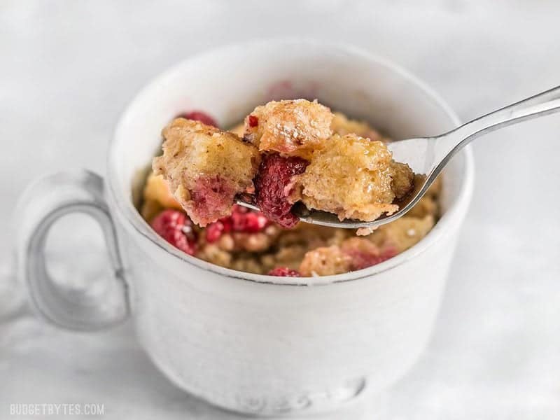These fast and easy 5-Minute French Toast Mugs are a great single serving breakfast treat plus a way to use leftovers and reduce food waste. BudgetBytes.com Close up of a forkful of a French Toast Mug with raspberries
