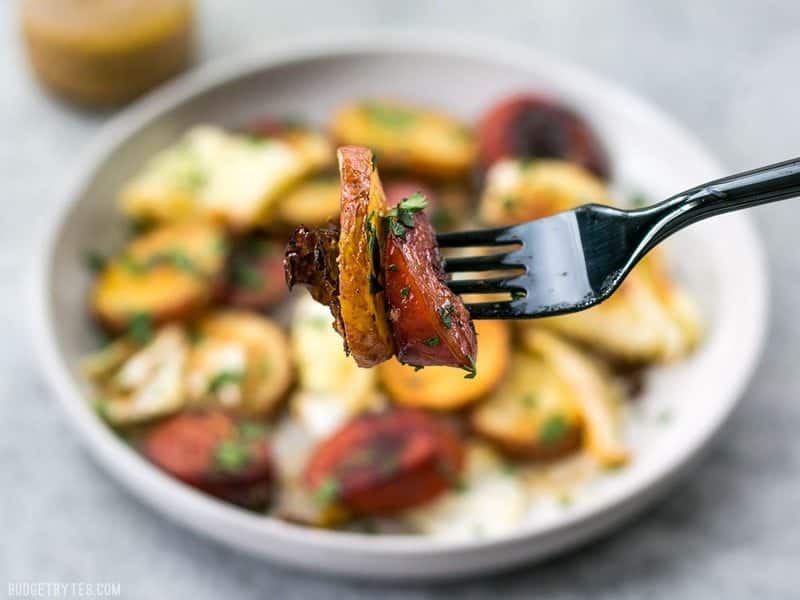 This One Pan Roasted Kielbasa and Cabbage Dinner comes together in minutes and is full of flavor and comfort. An easy weeknight dinner! BudgetBytes.com A forkful of Roasted Kielbasa and Cabbage with the plateful in the background